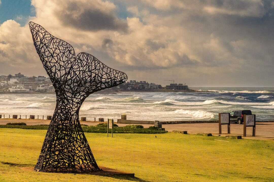 Golden hour sunset over La Mano sculpture in Punta del Este with ocean horizon
