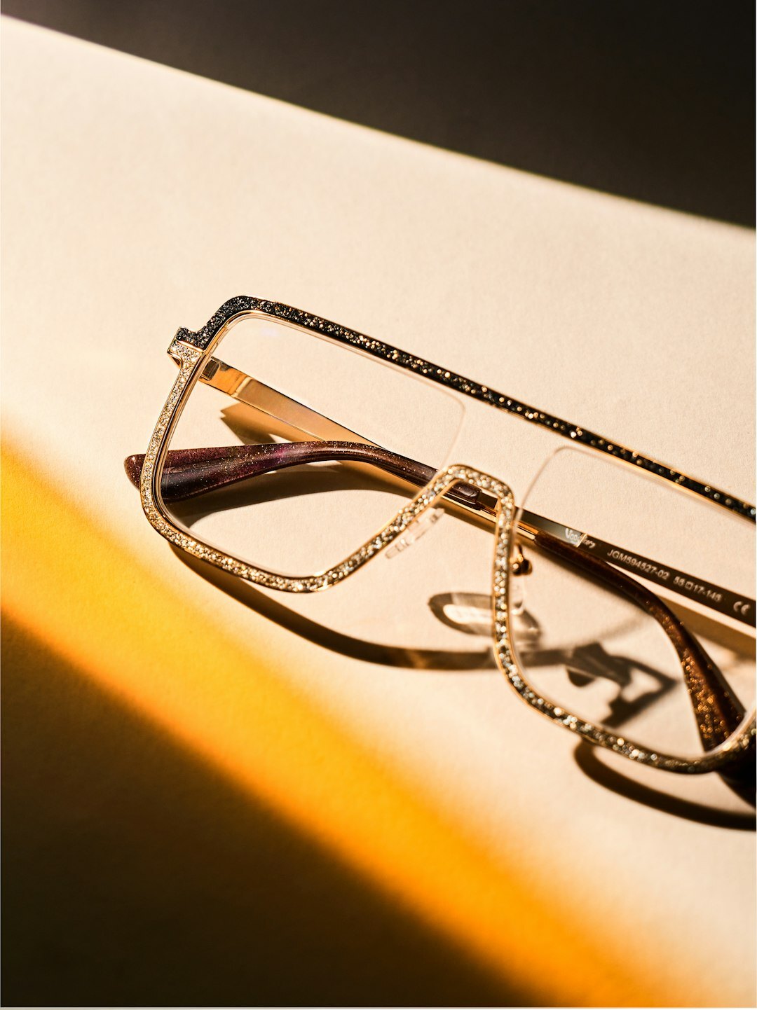 Macro photograph of a solid gold eyewear frame set with diamonds